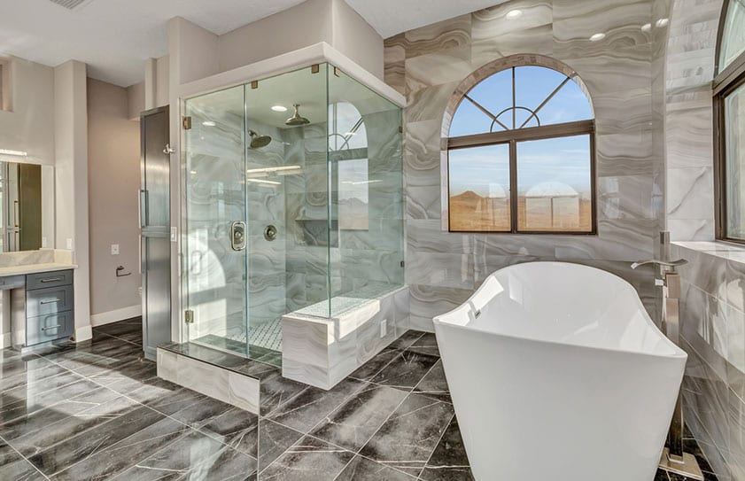 Beautiful modern bathroom with large tub, glass shower, and marble floors and walls